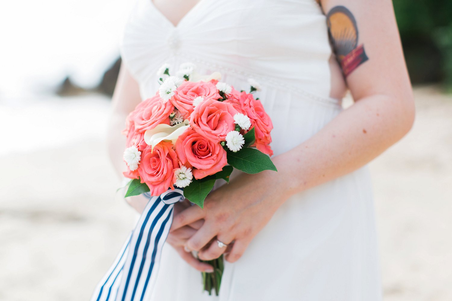 Coral rose bouquet with blue and white striped ribbon for tropical destination beach wedding.