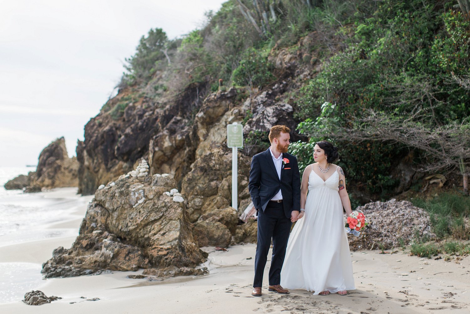 Bride and groom walk along Limetree beach after wedding ceremony.