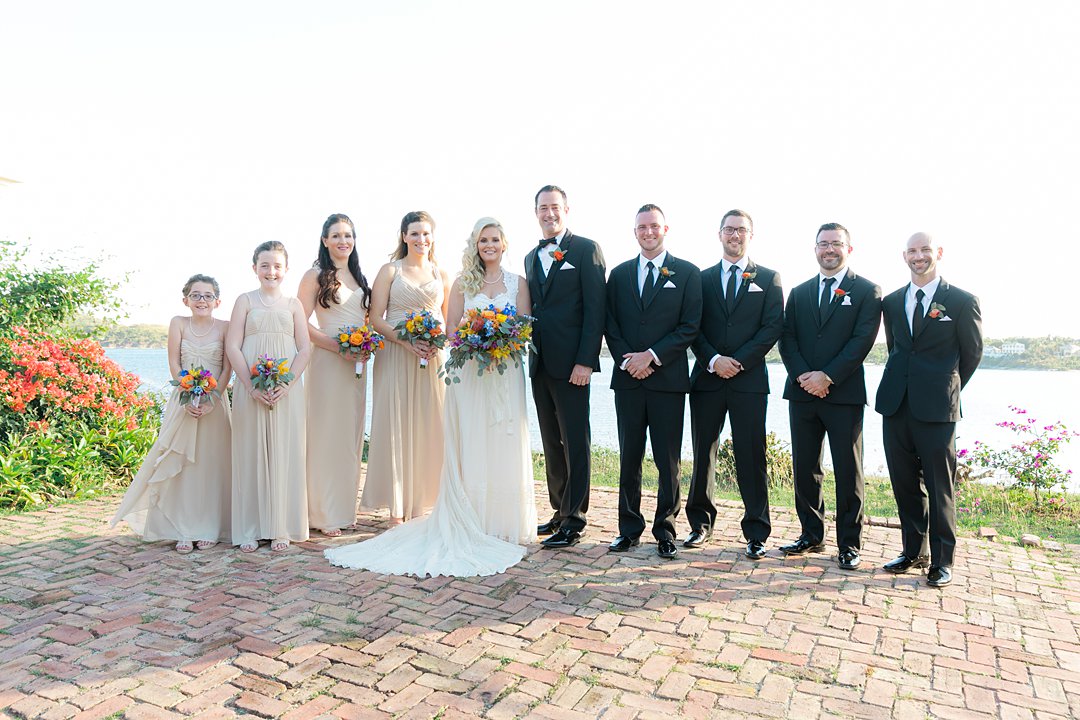Wedding party in formal black tuxes and nude dresses wit bright, tropical flowers for destination wedding.